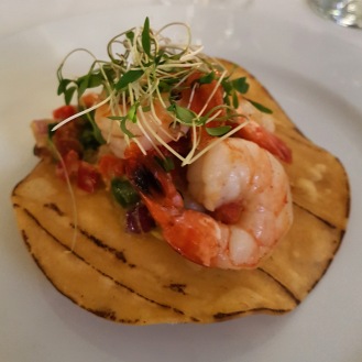 Shrimp on a tostada with guacamole and garnishes